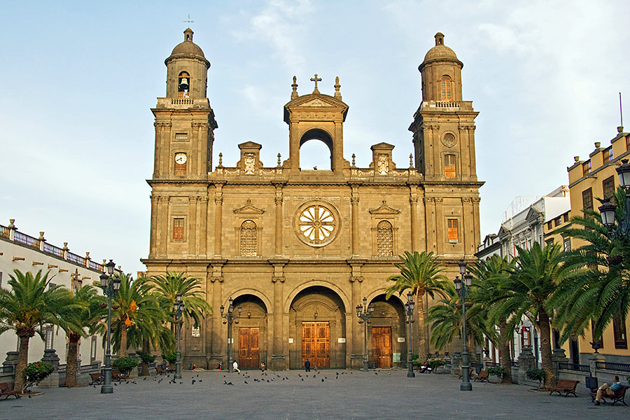 Katedra z dwoma wieżami. Do katedry prowadzą trzy duże wrota. Po bokach rosną palmy. Przed katedrą duży plac.